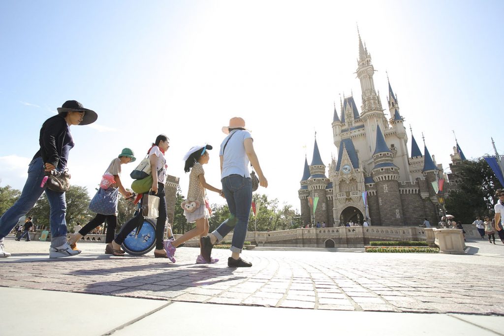 Photo of a young wheelchair user and family visiting a theme park