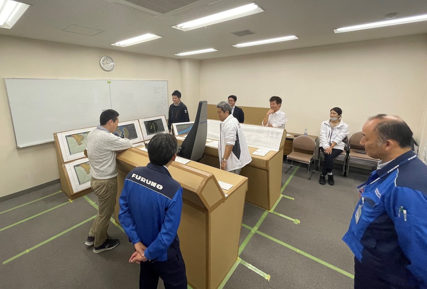 Photo of staff inspecting the arrangement of equipment for automated navigation on a forward bridge