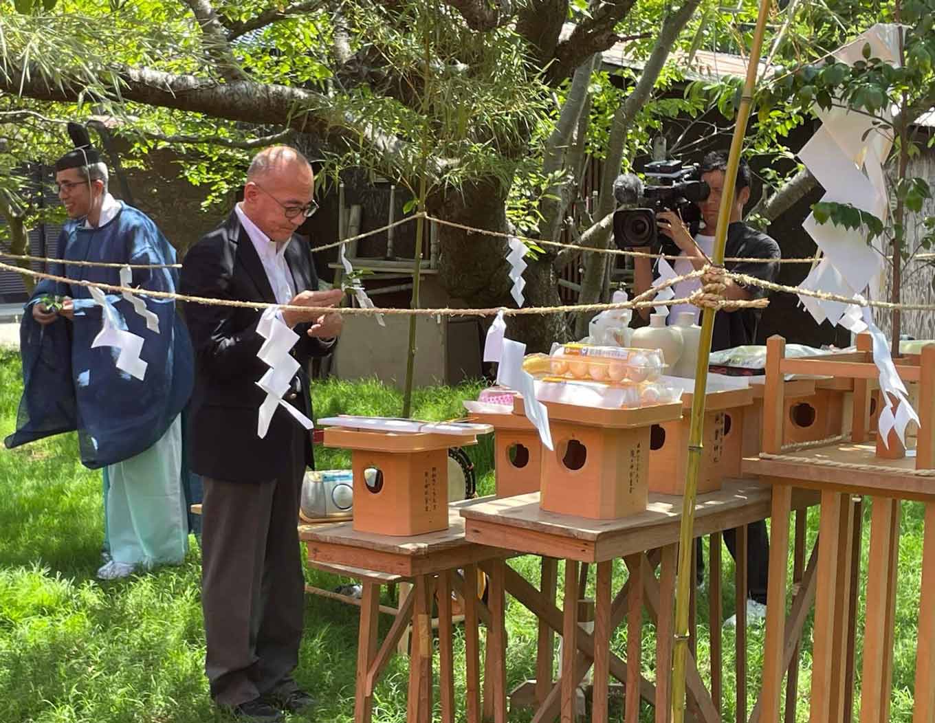 Photo of Hideo Sato standing in front of a Shinto altar