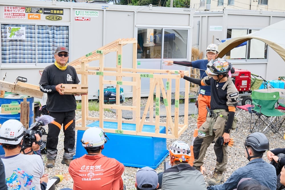 Photo: In the afternoon, the hands-on training using collapsed wooden houses finally began. Participants learned methods for lifting buildings with jacks, dismantling lumber with chainsaws, and entering buildings using crowbars, as well as essential safety knowledge for their work, such as recognizing signs indicating risk of building collapse during operations. When you stand before an actual collapsed wooden house, you realize that no two are the same. That is precisely why it is important not to learn from textbooks, but to accumulate experience through hands-on training. The workshop continued from early morning until evening. Even so, the participating firefighters showed no signs of fatigue. Their dedication to improving their own skills in order to save lives was deeply reassuring, and seemed to offer a glimpse of progress toward developing the disaster relief system.