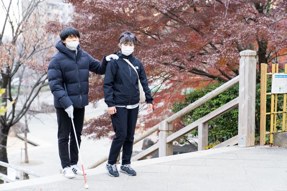 A guide helper accompanying a visually impaired companion
