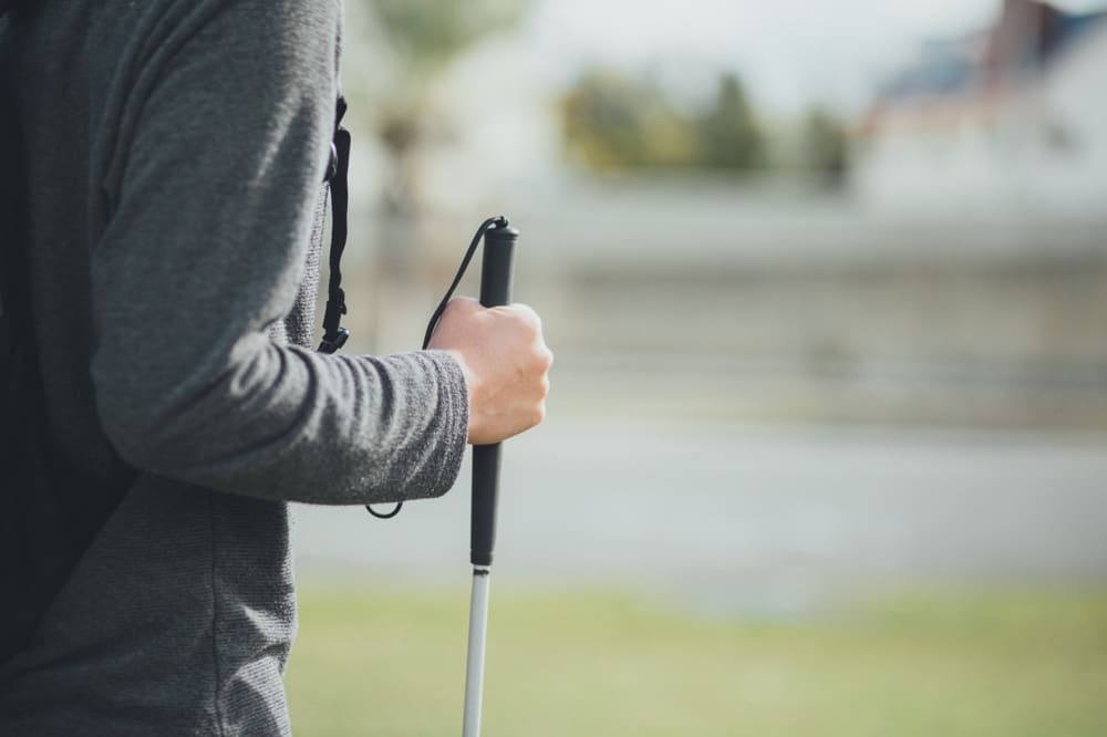 A visually impaired person using a white cane to navigate