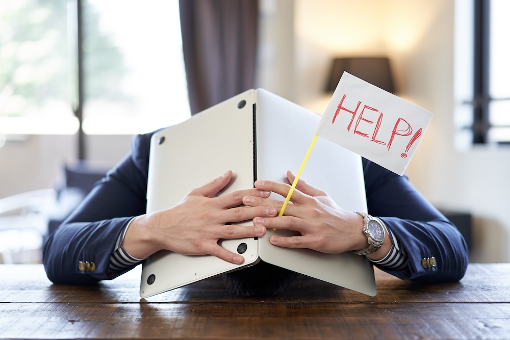 Photo (image): A man holding his head at a company desk