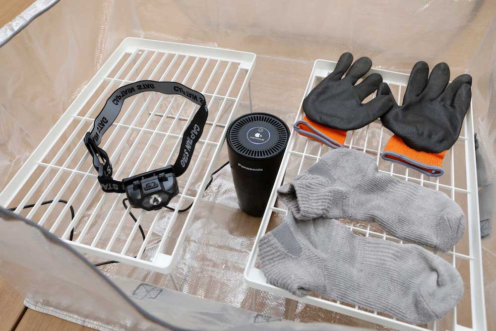 With the Anything Bag open, items prone to odor sit on the shelves inside. In the photo, a headlamp, rubber gloves, and socks are shown as examples.