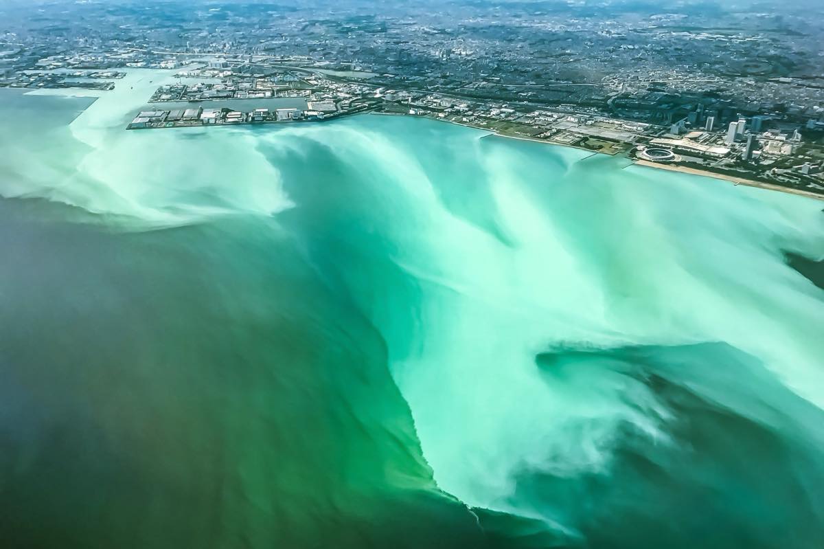 Photo of a section of the ocean that has turned a brilliant bluish-green from the formation of a blue tide