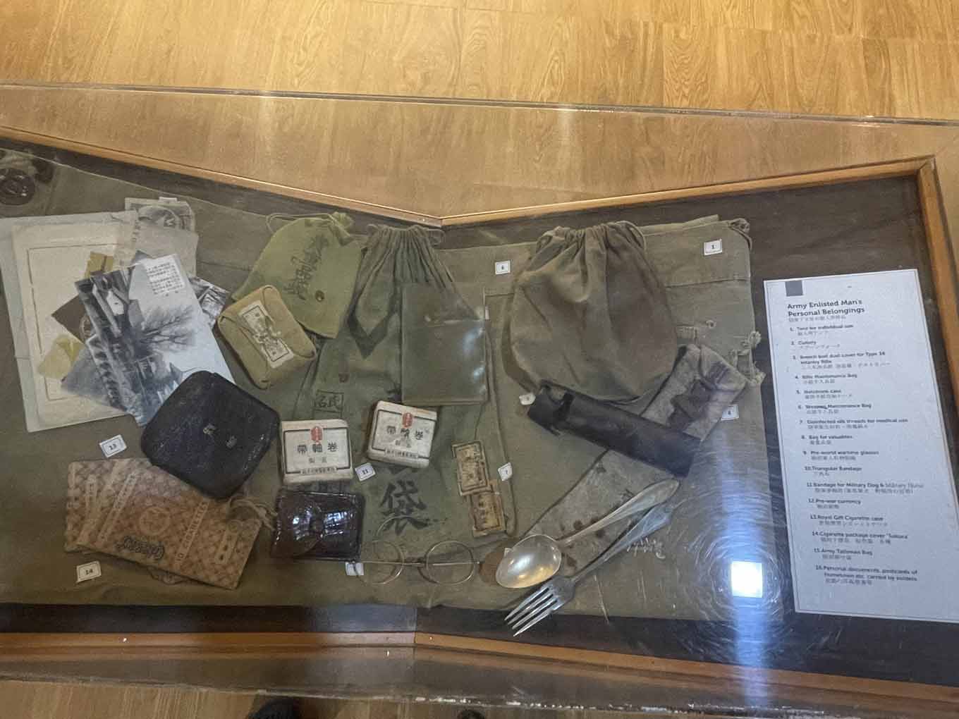 Photo of a display case in the museum’s war section showing a soldier’s personal belongings, including pouches, bags, documents, small cases, glasses, and a spoon and fork
