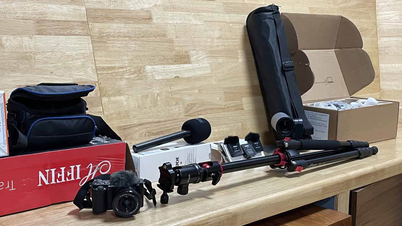 Photo of a digital camera, tripod, microphone, speaker, and webcam