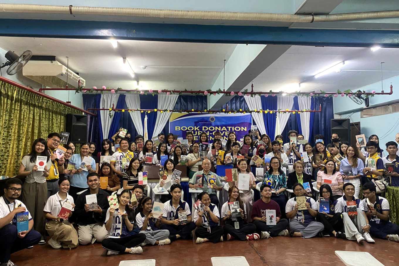 Group photo of students and teachers holding books