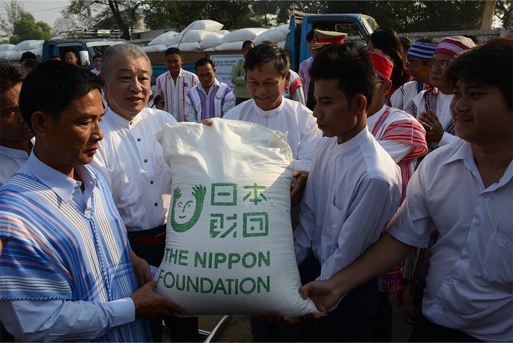 Photo of The Nippon Foundation Chairman Yohei Sasakawa delivering rice to grateful representatives of an ethnic group in Myanmar